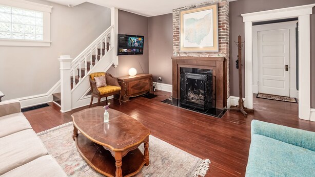 A living room with a fireplace, a staircase, and a TV mounted on the wall.