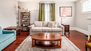 A living room with a sofa, a coffee table, a bookshelf, and a framed picture on the wall.