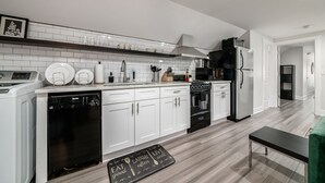 A modern kitchen with white cabinets, a black refrigerator, a dishwasher, and a microwave. - Columbus Getaway! Stylish Apartment! (Columbus)