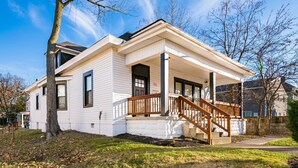 A two-story house with a front porch and a staircase leading to the entrance. - Columbus Getaway! Stylish Apartment! (Columbus)
