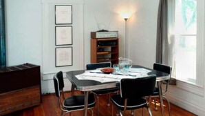 A dining area with a table set for four, surrounded by chairs, a vintage radio, and framed certificates on the wall. - Garden View Lodge (Lucas)