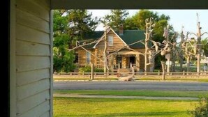 A porch with a view of a grassy area and a wooden building in the background. - Garden View Lodge (Lucas)
