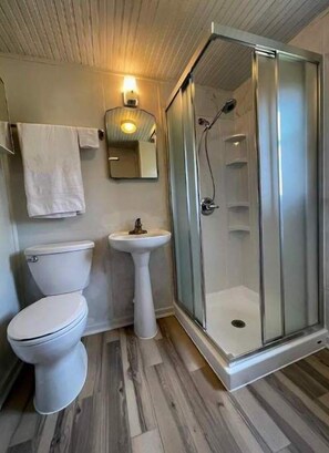 Enjoy a refreshing shower in this bathroom with a pedestal sink and glass-enclosed shower stall.
