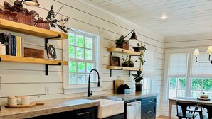 A kitchen with wooden shelves, a sink, and a dining area with chairs.