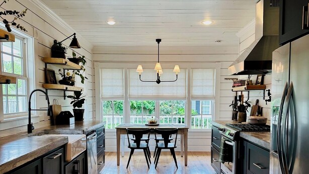 A kitchen with wooden floors, a dining table, and built-in appliances.