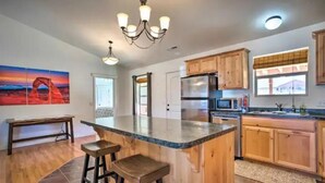 A spacious kitchen with wooden cabinets, a large island with stools, a refrigerator, and a microwave. - Moab Oasis among the Redrocks! (Moab)