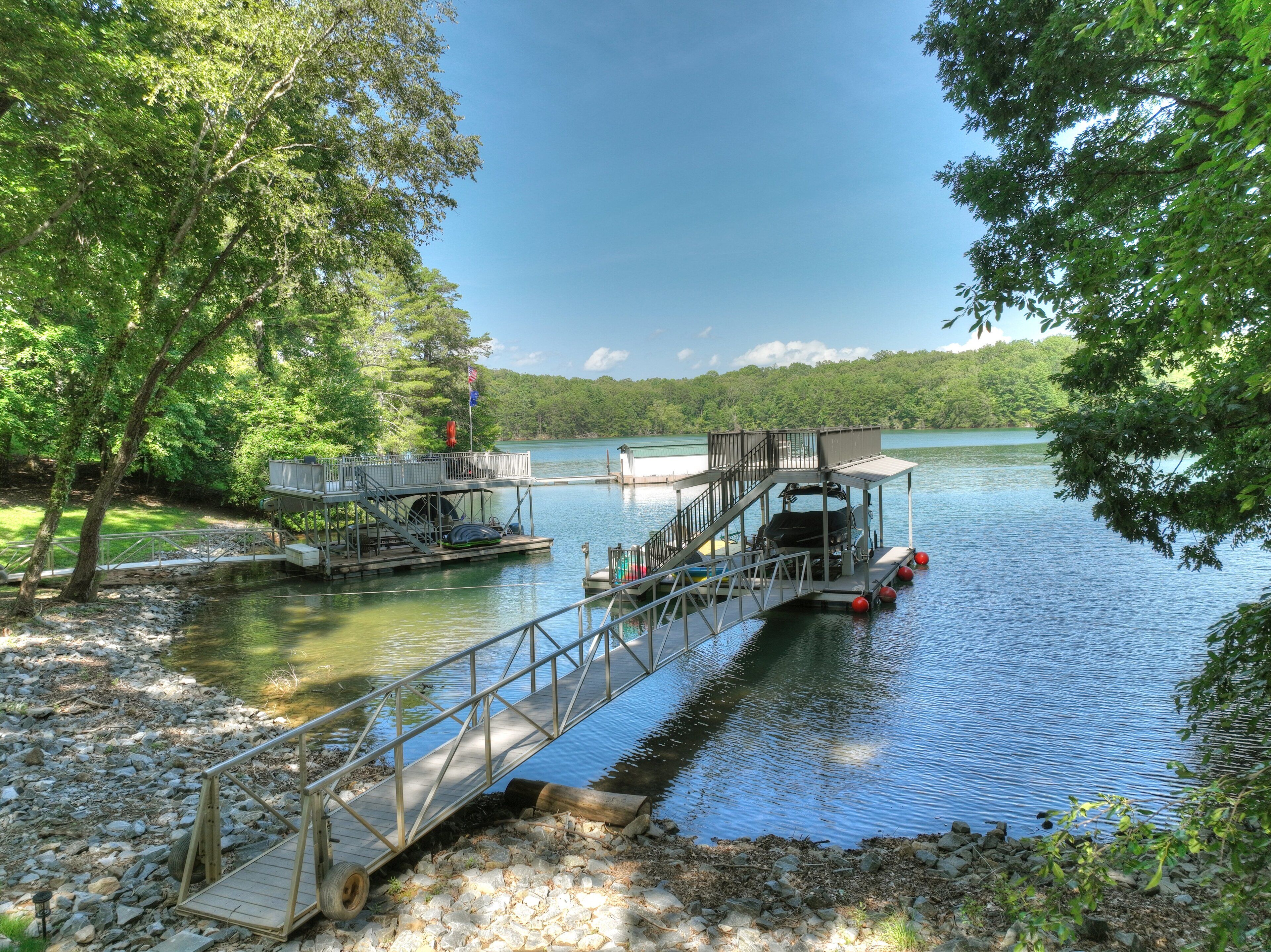 A dock with a wheelchair accessible ramp, a small boat, and a flagpole with flags.