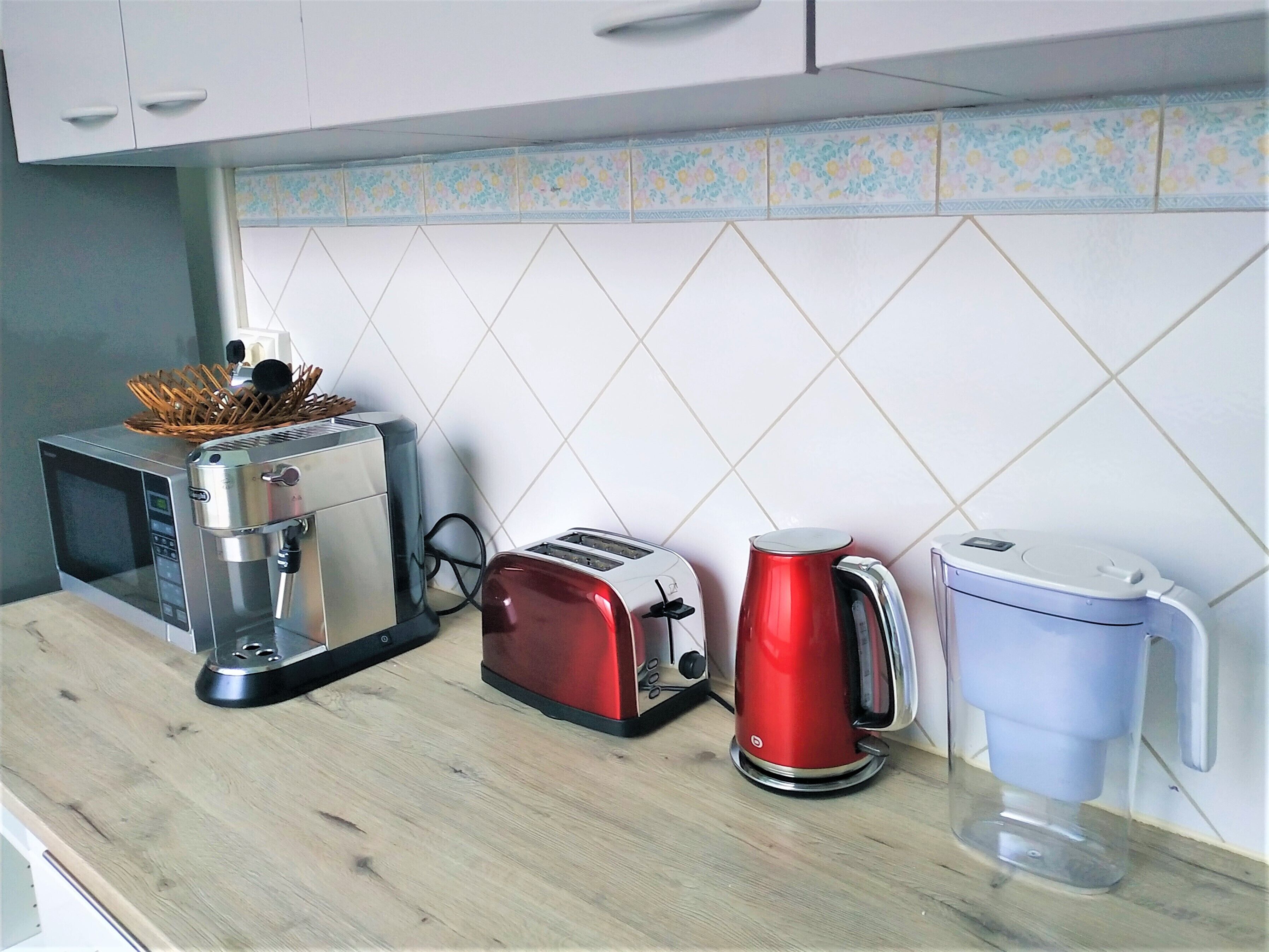 A kitchen with a coffee maker, toaster, and microwave on the counter.