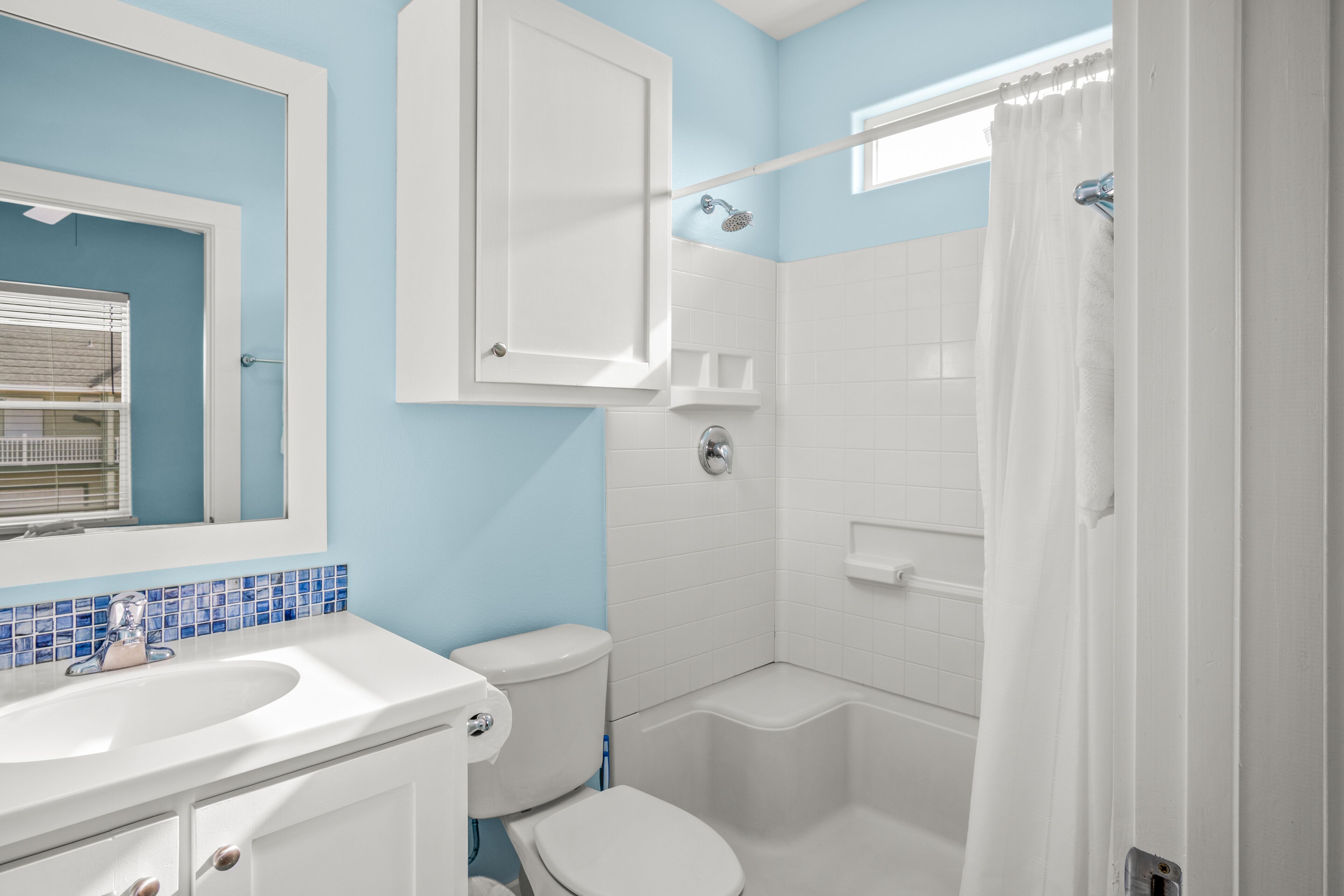 Une salle de bain avec un lavabo, des toilettes et une baignoire blancs, des murs bleus et un rideau de douche.