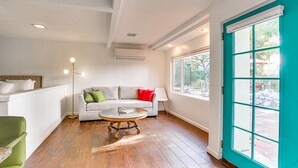 Una sala de estar moderna con un sofá, una mesita de centro y un ventanal con contraventanas color turquesa.