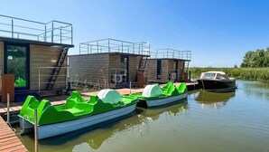 Eine moderne, schwimmende Struktur mit vor Anker liegenden grünen Booten, einem überdachten Außenbereich und einem Boot im Hintergrund.