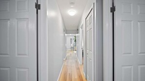 Un corridoio con porte bianche, pavimento in legno e illuminazione a incasso.