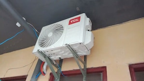 An air conditioning unit mounted on a metal stand attached to a building's exterior wall. - TerisitaPlace - Love At First (Taytay)