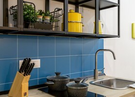 Una cucina con piastrelle blu, un lavello, un portacoltelli e pentole sul bancone.