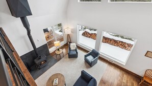 Un salon moderne doté d’une cheminée, de sièges confortables et de grandes fenêtres offrant une vue sur l’extérieur.