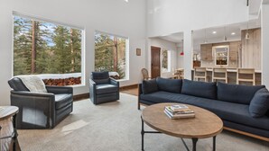 Un salon moderne avec une grande fenêtre, un canapé, une table basse et une cheminée.