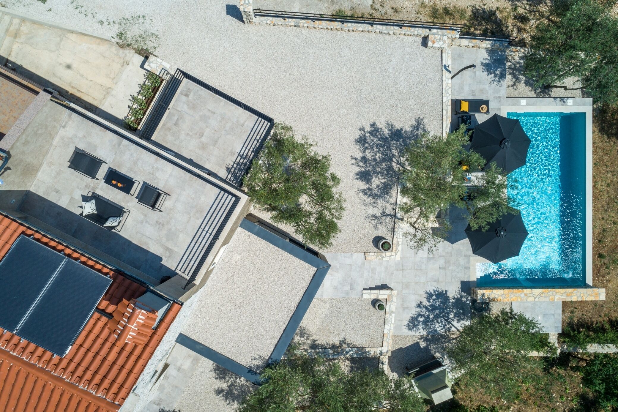 Oversigtsbillede af en ejendom med swimmingpool, udendørs siddepladser og tagterrasse.