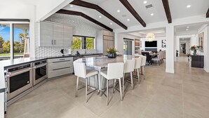 Uma cozinha ampla com uma ilha grande, eletrodomésticos modernos e vista para o exterior.