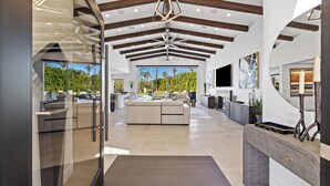 Ampla sala de estar com um sofá grande, cozinha e vista para um jardim exuberante.