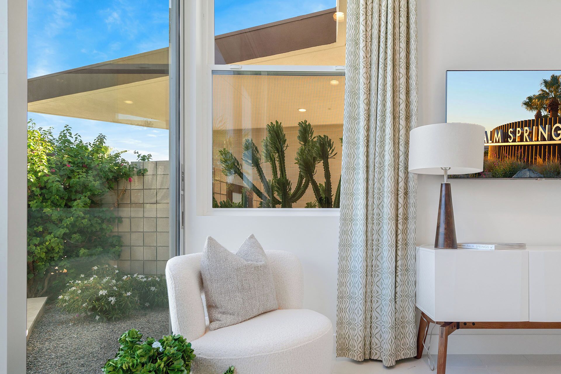 A modern living room with a white sofa, a patterned curtain, and a lamp.