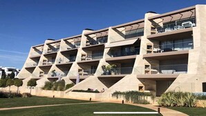 A modern building with multiple balconies and a flat roof.