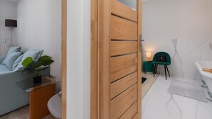 A modern bathroom with a white bathtub, a green chair, and a small table with a plant. - house 5 miles to an Old Town with double walk-in shower and Victorian tub (Borkowo)