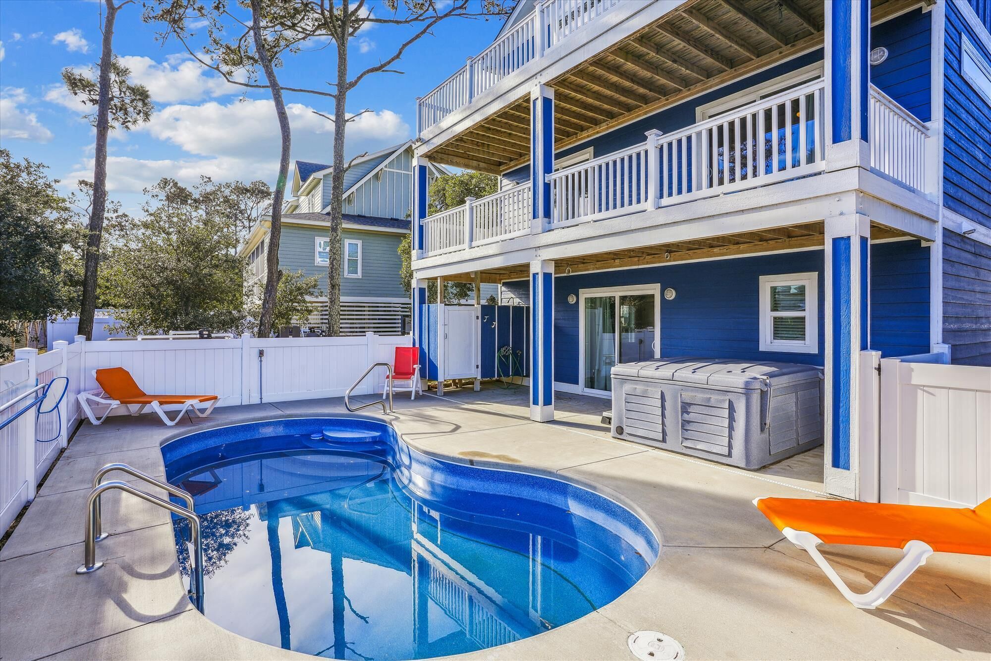 A two-story building with a pool, outdoor seating, and a covered patio area.