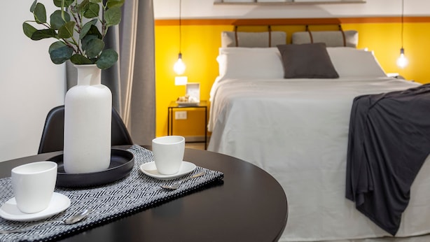 A hotel room with a bed, bedside table, and a vase with green leaves. - Ghiberti - Lovely nest in the city (Trieste)