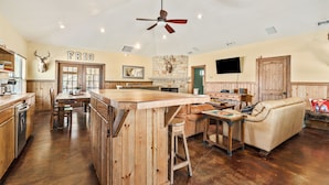 Une cuisine spacieuse avec des meubles en bois, un îlot central et une cheminée en pierre.