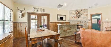 A rustic interior with a wooden dining table, a stone fireplace, and a leather couch.