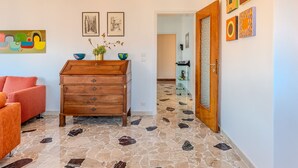 A room with a wooden dresser, a red sofa, and a hallway leading to another room.