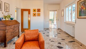 A hallway with a wooden dresser, a cushioned chair, a decorative door, and artwork on the walls.