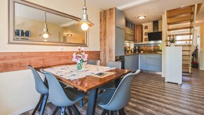 Un coin repas avec une table en bois, des chaises bleues et un vase de fleurs.