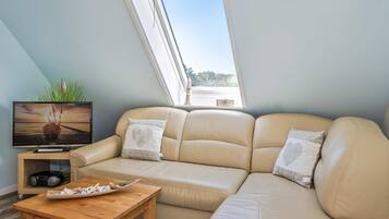 A modern living room with a sofa, a television, and a wooden coffee table.