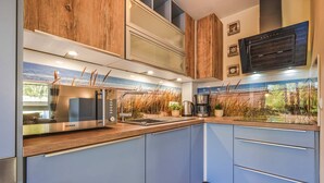 Une cuisine moderne équipée d’un four à micro-ondes encastré, d’une machine à café et offrant une vue sur l’extérieur grâce à une fenêtre.