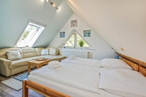 A bedroom with a bed, a sofa, a window, and a radiator.
