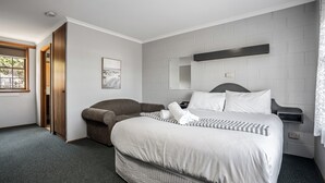 A hotel room with a large bed, a sofa, a wooden door, a window, and a mirror on the wall. - Bridport Bay Inn (Bridport)