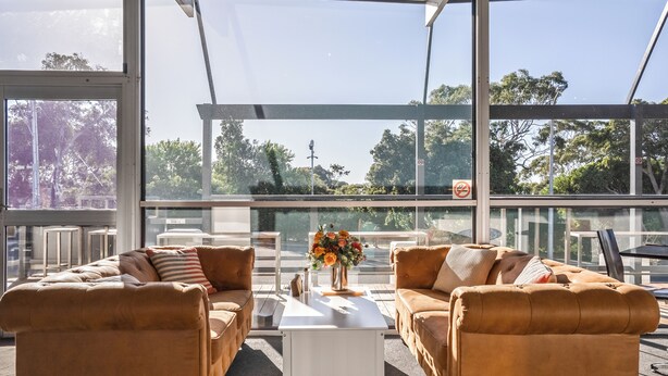 A modern outdoor seating area with two leather sofas, a white coffee table, and a vase of flowers. - Bridport Bay Inn (Bridport)