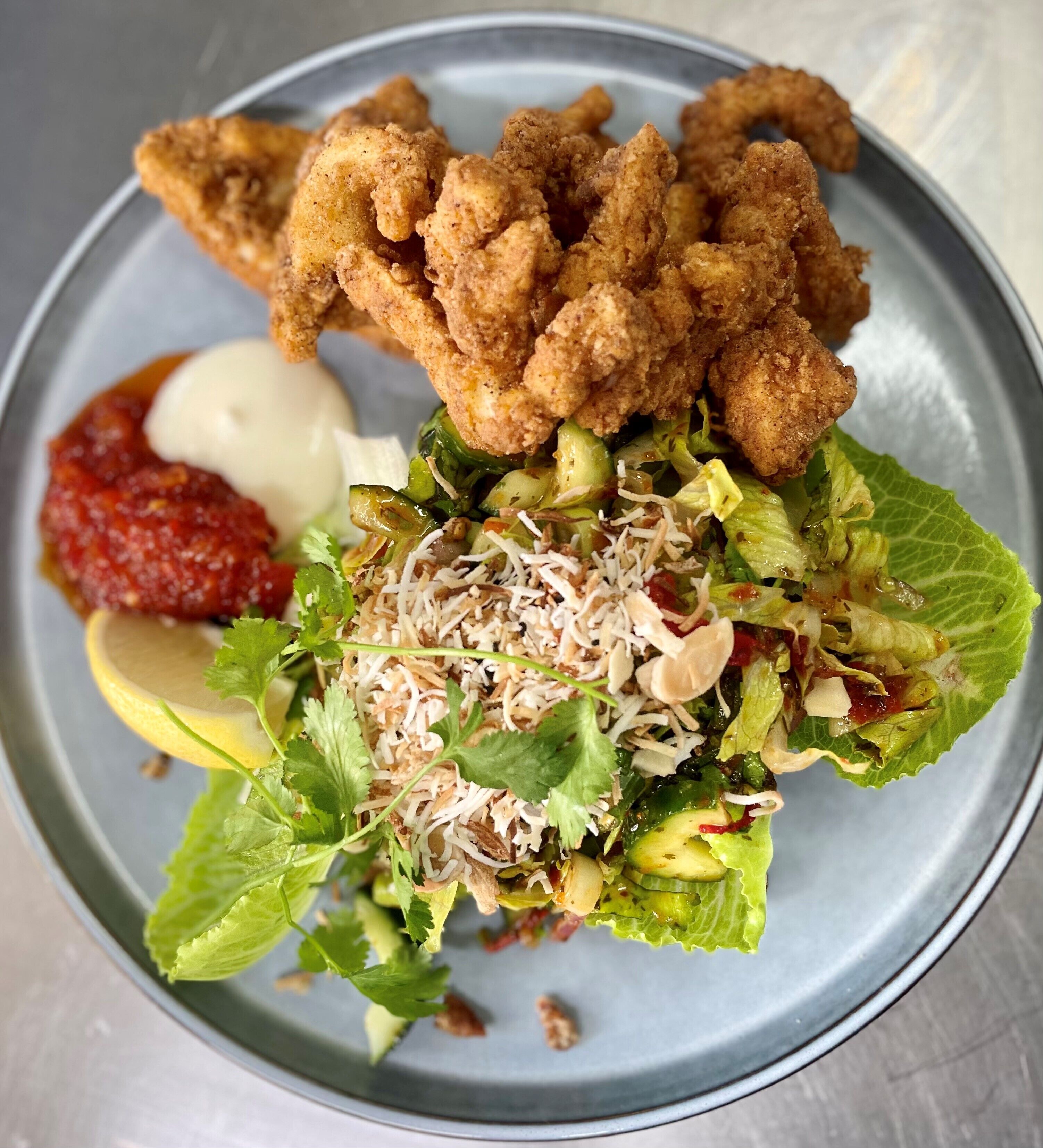 Une assiette de poulet frit, une salade et une portion de sauce à part.