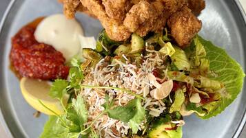 Une assiette de poulet frit, une salade et une portion de sauce à part.