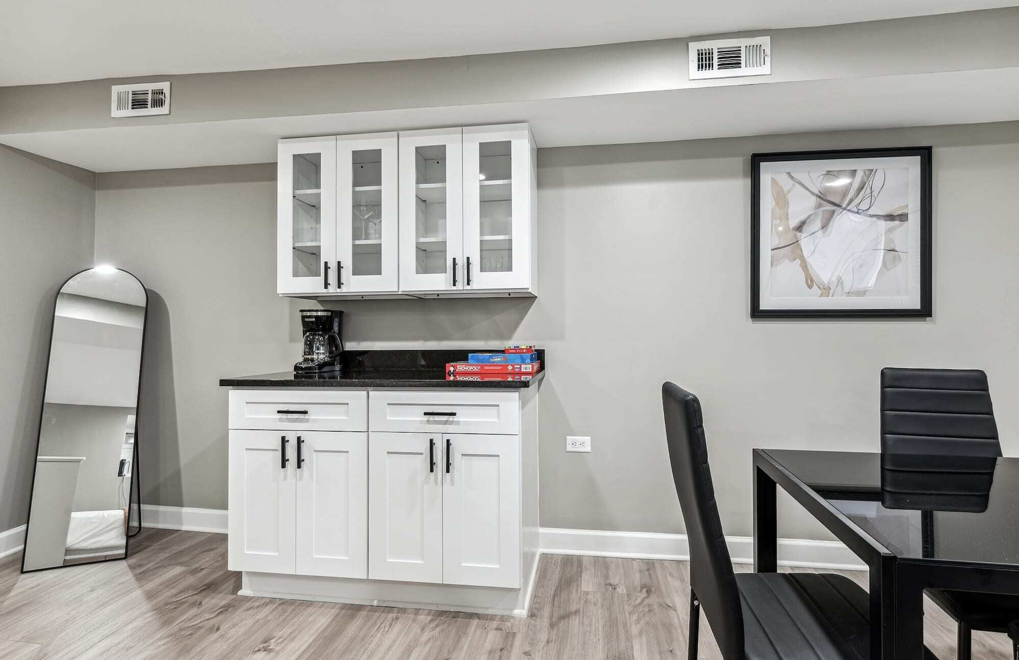 A kitchen with white cabinets, a coffee maker, and a framed picture on the wall.
