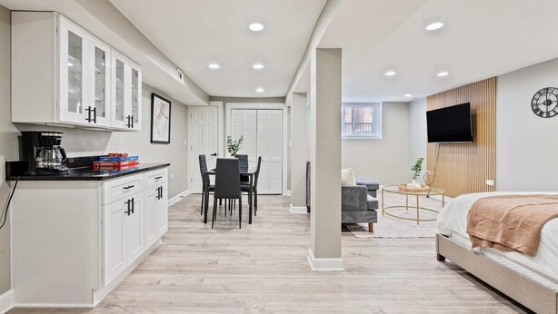 A modern bedroom with a bed, a TV, and a dining area with chairs and a table.