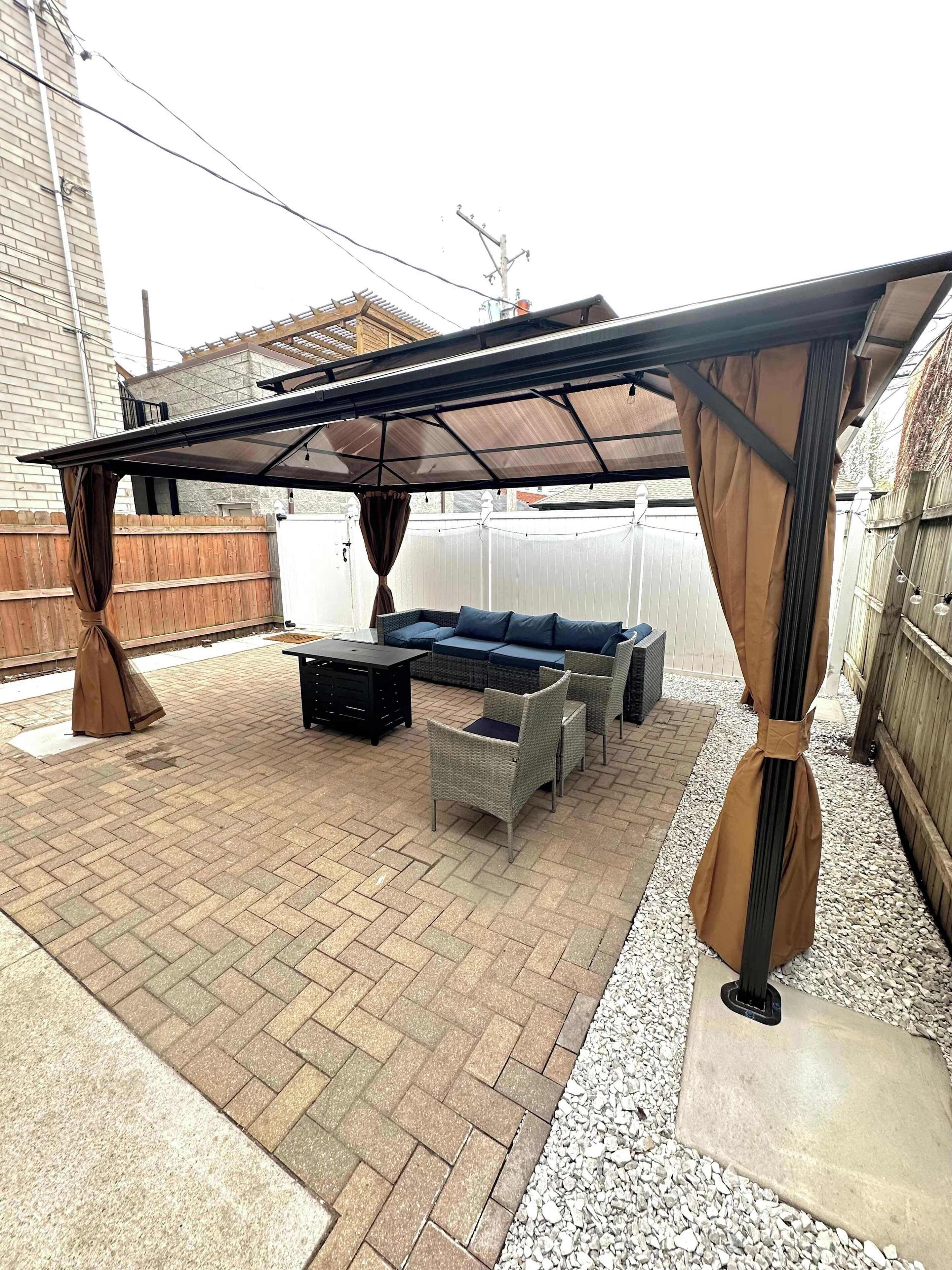 A covered patio area with outdoor furniture, including a sofa and chairs, and a pergola structure.