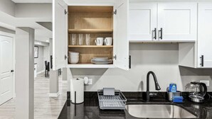 A modern kitchen with white cabinets, a black countertop, and a built-in dishwasher.