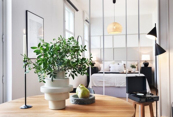 Relax in a serene space with a large window, a comfortable bed, and a bedside table with a lamp.
