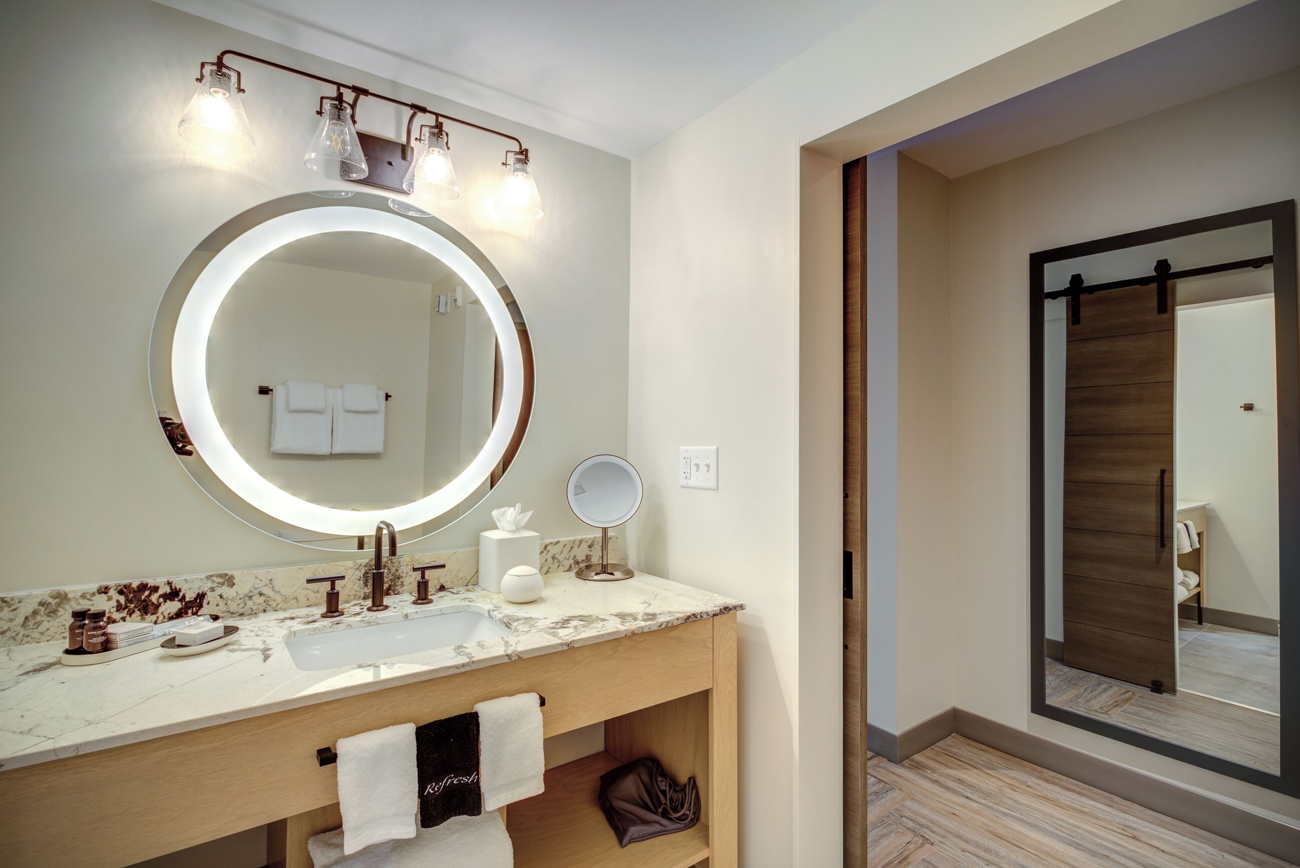 A modern bathroom with a large mirror, a round vanity, and a shower area.