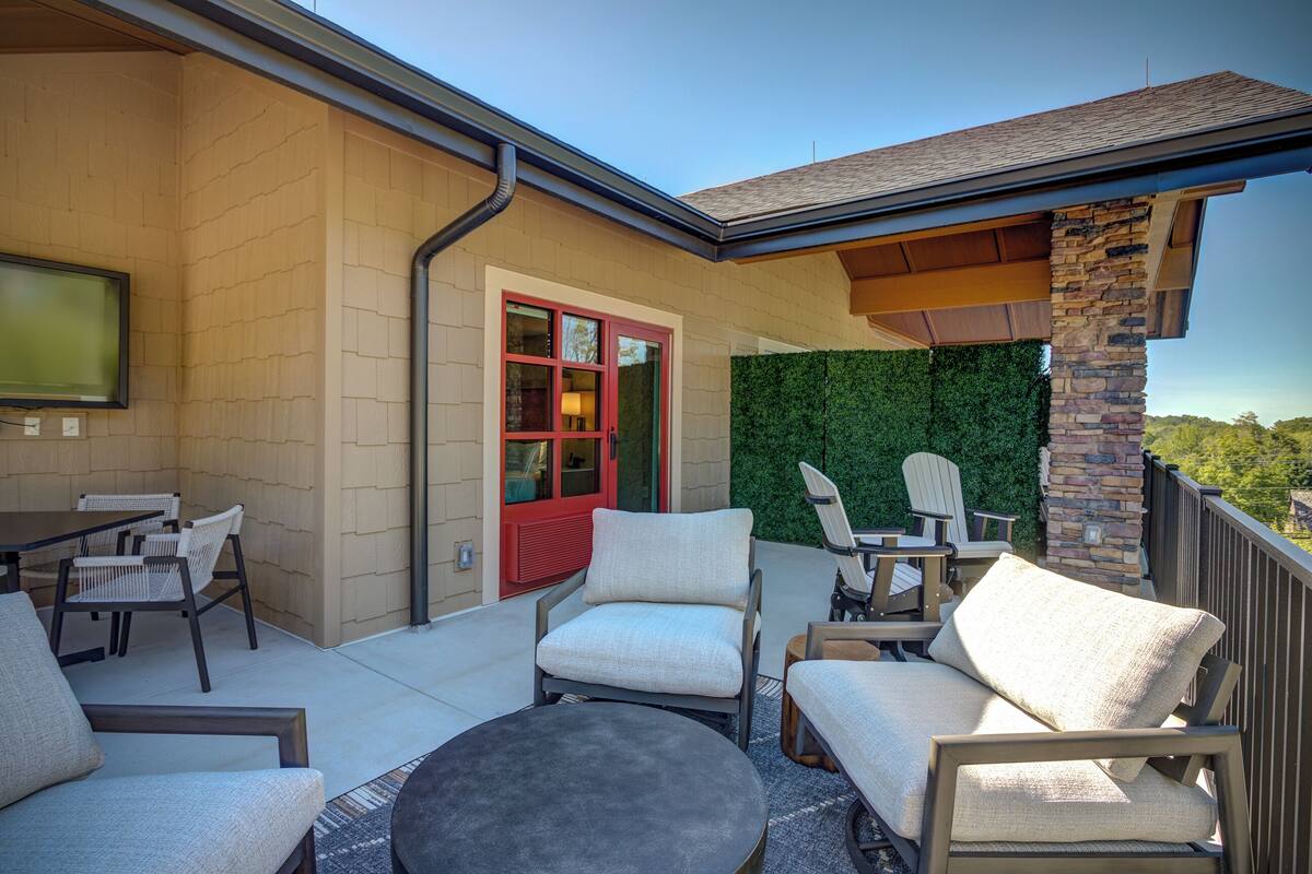 An outdoor patio with seating, a TV, and a red door.