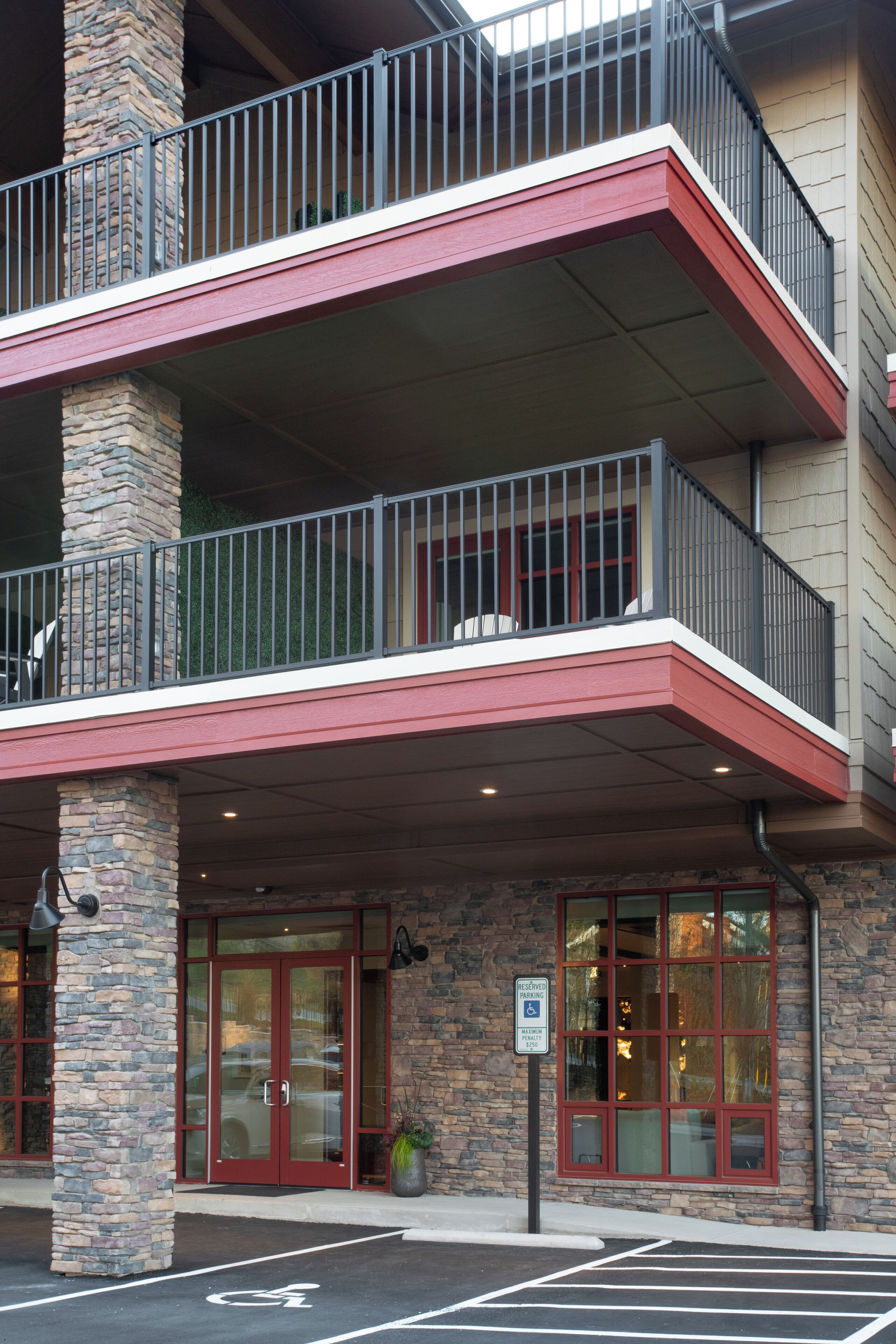 Ein Hotel mit rotem und beigem Fassadentyp, einer Steinsäule und einem Balkon mit Metallgeländern.