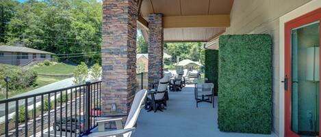 A covered outdoor seating area with stone pillars, green wall, and outdoor furniture.