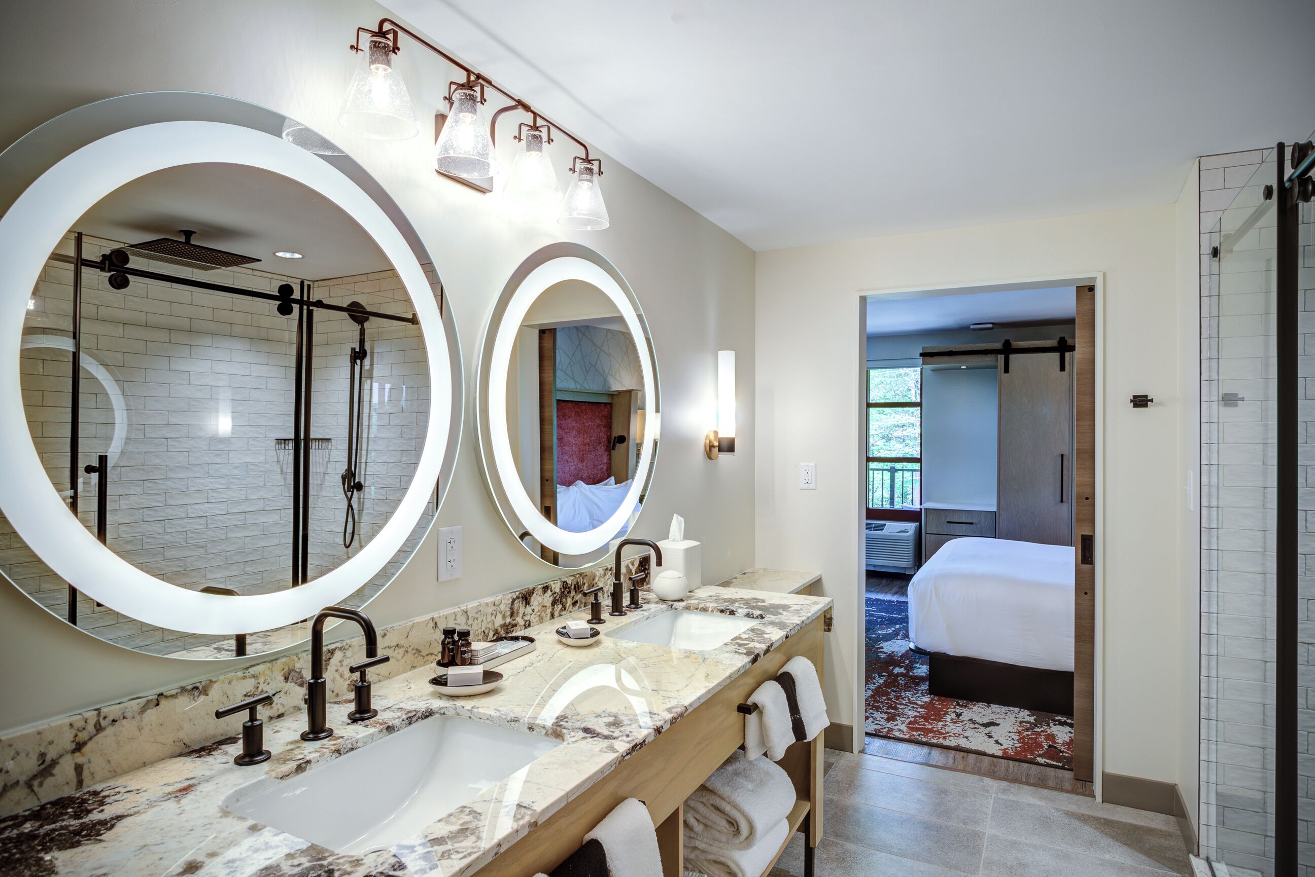 A modern bathroom with two large mirrors, a marble sink, and a shower area.